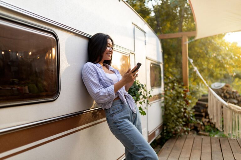 Woman leaning on her motorhome on an autumn camping trip