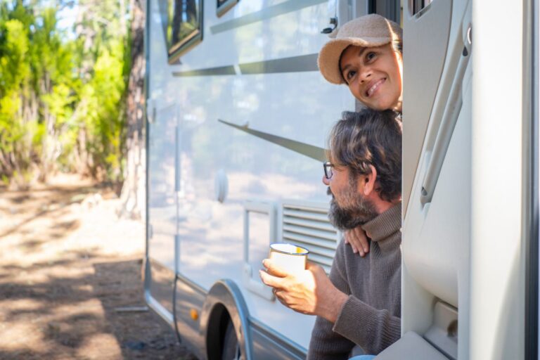 Couple sitting at the door of their motorhome on a long RV stay