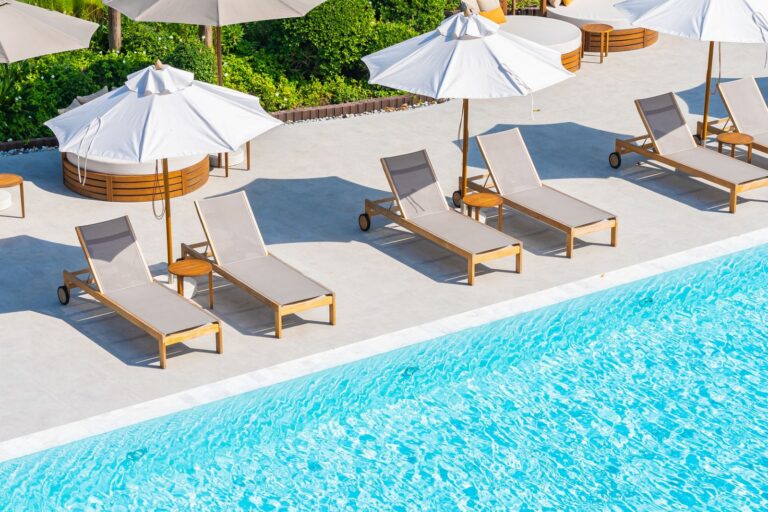 Lounge chairs and umbrellas beside an outdoor pool in summer